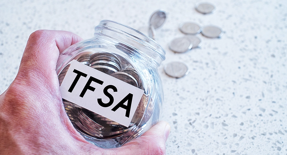 A hand holding a savings jar labelled TFSA